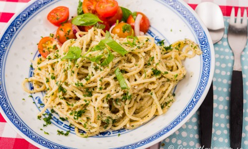 Solrospeston blandad med spagetti och serverad på tallrik med tomatsallad. 