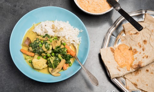 Vegansk gryta med grönsaker och curry serverad med ris, bröd och paprikahummus. 