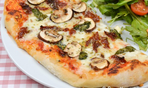 Vegetarisk pizza med soltorkad tomat, champinjoner och färsk basilika. 