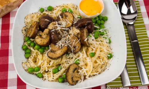 Vegetarisk spagetti eller pasta Carbonara med svamp - här skogschampinjon - grädde, gröna ärtor, svartpeppar, parmesan och äggula. 