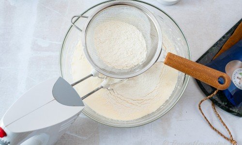 Blanda vetemjöl med bakpulver och sikta ner i äggsmeten. 