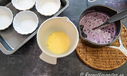 Koka upp socker, mjölk, grädde, blåbär och urskrapad vaniljstång. Vispa ihop ägg. 