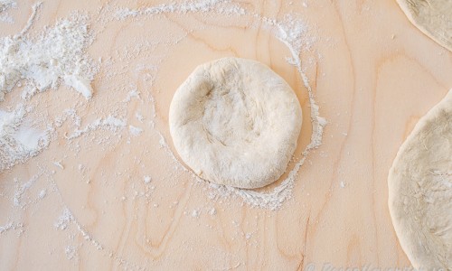 Tryck ut pizzadegen till en rundel och arbeta ut degen med händerna eller en kavel. 