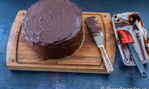 På och runt hela tårtan breds chokladglasyren. 