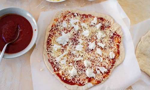 Lägg först på pizzasås, sedan ost och valfria toppings. 