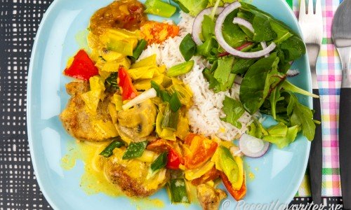 Fläskfilégryta med curry serverad med ris och grönsallad på tallrik. 