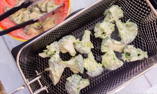 Vänd broccolibuketterna i frityrsmeten och lägg i fritösen. 