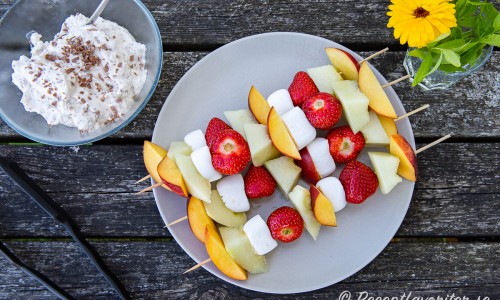 Fruktspetten innan grillning på tallrik med Daimgrädden vid sidan. 