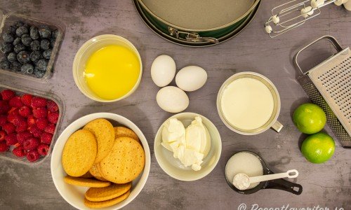 Ingredienser till den frysta cheesecaken: Digestivekex, smält smör, ägg, färskost, socker, vaniljsocker, grädde, lime samt hallon och blåbär till garnering. 
