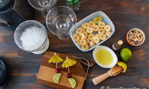 Ingredienser till den alkoholfria banandaiquirin: krossad is, sockerlag, Sprite, ljus romessens, fryst banan, färskpressad lime och garnering med lime, cocktailbär och paraply. 