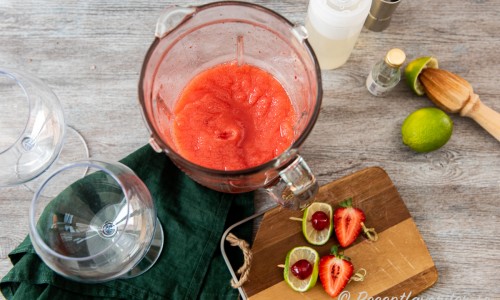 Is, lime, romessens, sockerlag och jordgubbar mixas till en slushig isröra. 