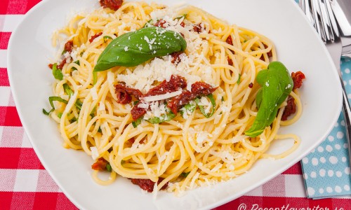 Glutenfri spaghetti med soltorkade tomater och basilika i tallrik