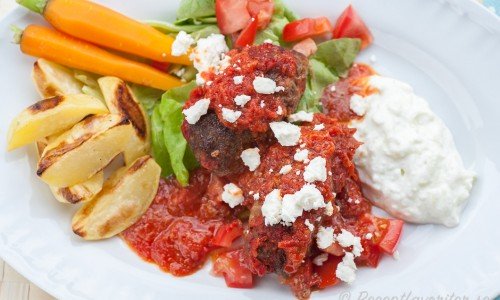 Grekisar - köttfärsbiffar i tomatsås med tillbehör på tallrik