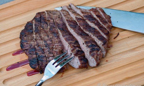 Flanksteken skärs i sneda skivor tvärs emot köttfibrerna till servering. 