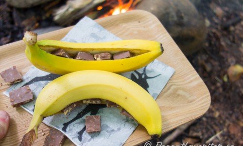Skär ett snitt i bananerna - dock ej ända genom - och tryck in chokladbitar. 
