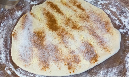 Degen kavlas ut på mjölat bakbord och så brer man på mjukt smör samt strör över socker och kanel. 