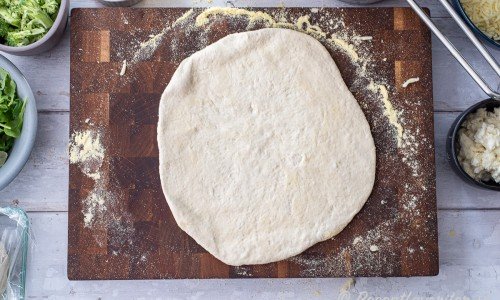 Knåda ut degen till en rundel på ca 30 cm diameter. Du kan ta majsmjöl eller vanlig vetemjöl under samt vetemjöl över när du knådar ut. Använd ev. kavel om du ej får ut med händerna. 