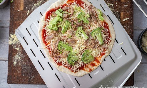 Pizzan toppas med tomat- pizzasås, riven mozzarella, färsk mozzarella, broccoli, kycklingkött och bakas sedan. 