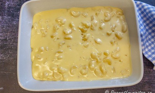 Makaronerna blandas med sås och ost samt breds ut i en ugnsfast form. 