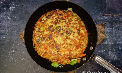När okonomiyakin stelnat och fått fin färg på undersidan vänds den och så steker man lite till på medelvärme tills den får fin färg. 