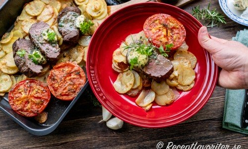 Oxfilé Provencale med vitlökssmör på en bädd av skivad råstekt potatis och kantat av mogna goda tomater. 
