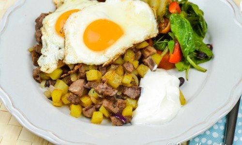 Pyttipanna med oxfilé, potatis och lök samt stekta ägg, crème fraiche och en grönsallad. 