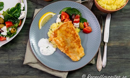 Knaperstekt panerad gösfilé serverade med kall dillsås, krossad potatis, citron och sallad. 