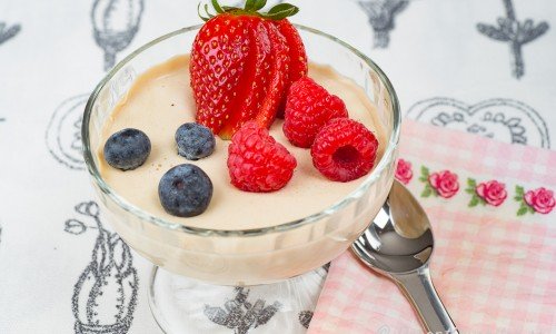 Pannacotta smaksatt med lakrits serverad i coupeglas till dessert garnerad med färska hallon, blåbär och jordgubbe. 