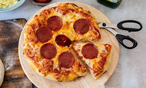Ta ur pizzan ur panna och servera varm i slicar du klipper med sax eller skär med kniv. 