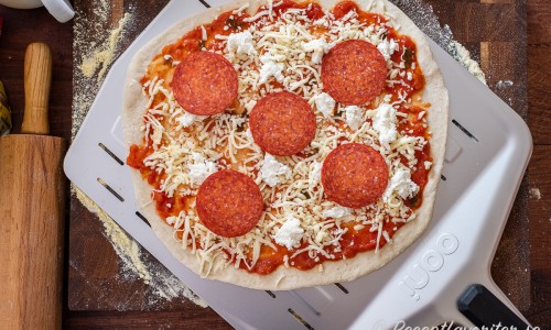 Bred först ut pizzasås, sedan riven mozzarella, grovt delad färsk mozzarella samt så mycket pepperoni salami du önskar. 
