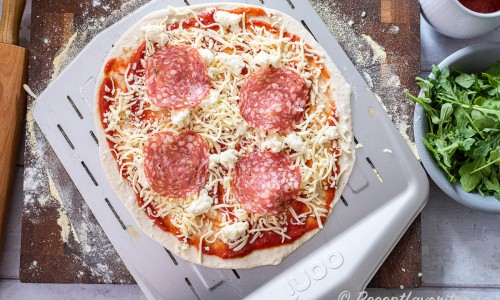 Lägg på pizzasås, riven mozzarella och Västerbottenost samt 4-5 skivor tryffelsalami. 