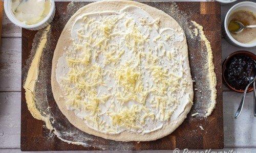 Knåda ut till en rundel på ca 30 cm diameter och toppa med ett tunt lager crème fraiche samt sprid ut riven mozzarella. 