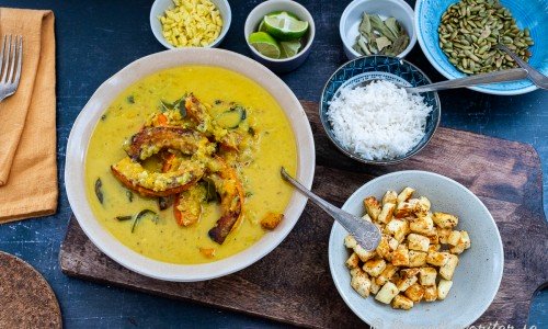 Servera pumpacurryn med tillbehören vid sidan: färsk hackad ingefära, lime, basmatiris, pumpafrön och grillost. 