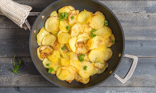 Skivad råstekt potatis i panna till oxfilé provencale. 