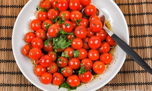 Små tomater i balsamvinäger och bladpersilja serverade på fat