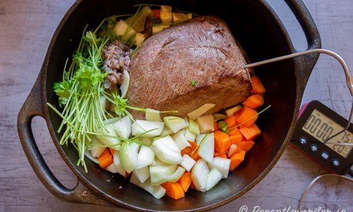 Steken bryns och läggs med grönsaker runt i grytan samt en stektermometer i mitten av köttet. 