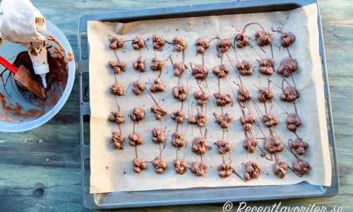 När trillingnötterna stelna tillsammans så garneras de med smält choklad med lite extra mörk choklad i för att få en lite mörkare färg på garneringen. 