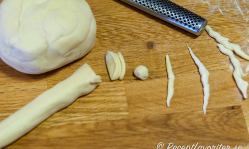 Pastadegen skärs i små bitar och rullas till sneda skruvar för hand. 