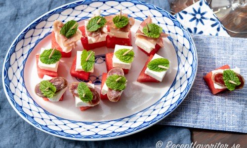 Tilltugg med vattenmelon i tärningar på tandpetare serverade på fat