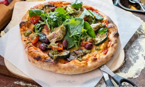 Lägg på övriga valfria toppings som babyspenat, rucola, basilika, oliver och kronärtskocka samt skeda över lite pesto. 