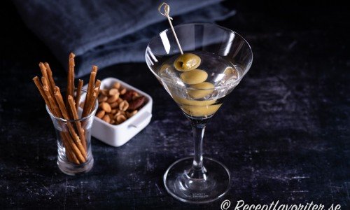 Vodka Martini med oliver i martiniglas serverad som aperitif innan maten med salta pinnar och nötter. 