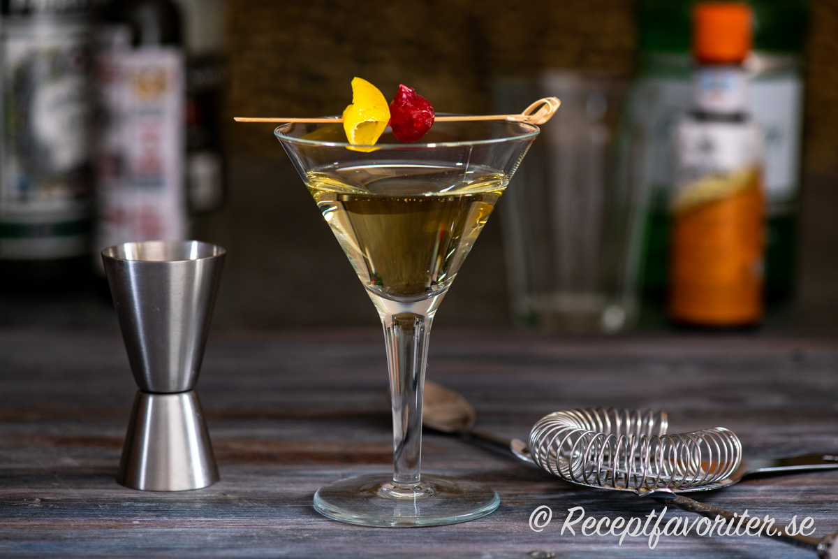 Tuxedo cocktail i martiniglas serverad med citronskal och maraschinococktailbär. 