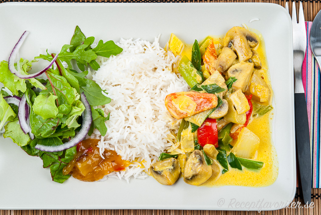 Vegetarisk currygryta med grönsaker serverad med ris, chutney och grönsallad på tallrik.