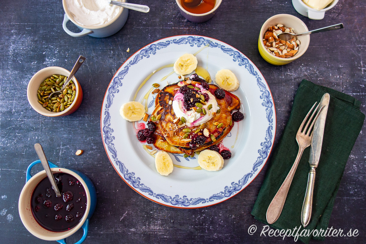 Pannkaksfest med tjocka amerikanska pannkakor med vaniljkvarg, björnbär, banan, sirap, mandel och pumpafrön. Pannkaksfest med tjocka amerikanska pannkakor med vaniljkvarg, björnbär, banan, sirap, mandel och pumpafrön.