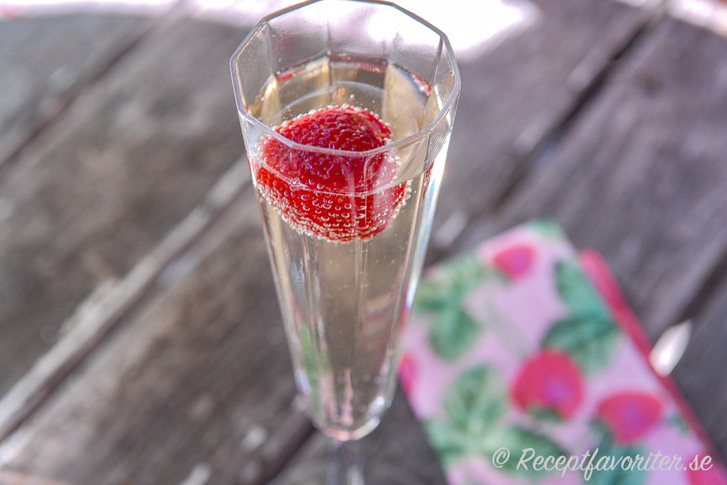 Ett glas läskande Champagnebål med jordgubbe Ett glas läskande Champagnebål med jordgubbe