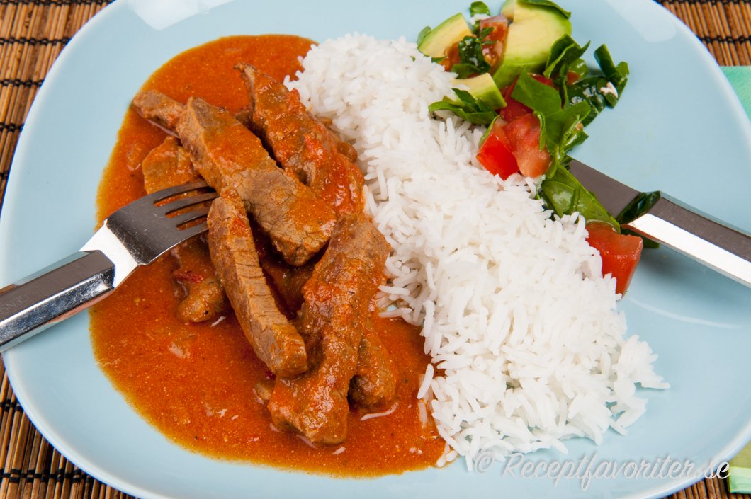 Stroganoff lagad med mört biffkött serverat på tallrik med kokt ris och grönsallad Stroganoff lagad med mört biffkött serverat på tallrik med kokt ris och grönsallad