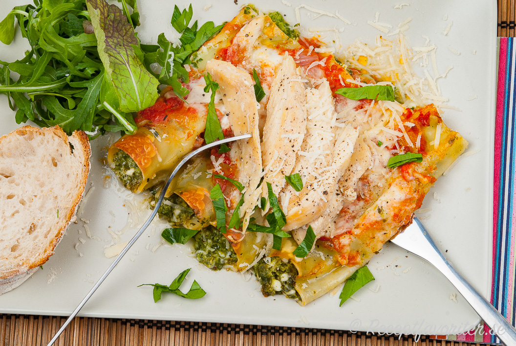 Cannelloni toppad med stekt kycklingfilé på tallrik med sallad och bröd till. Cannelloni toppad med stekt kycklingfilé på tallrik med sallad och bröd till.