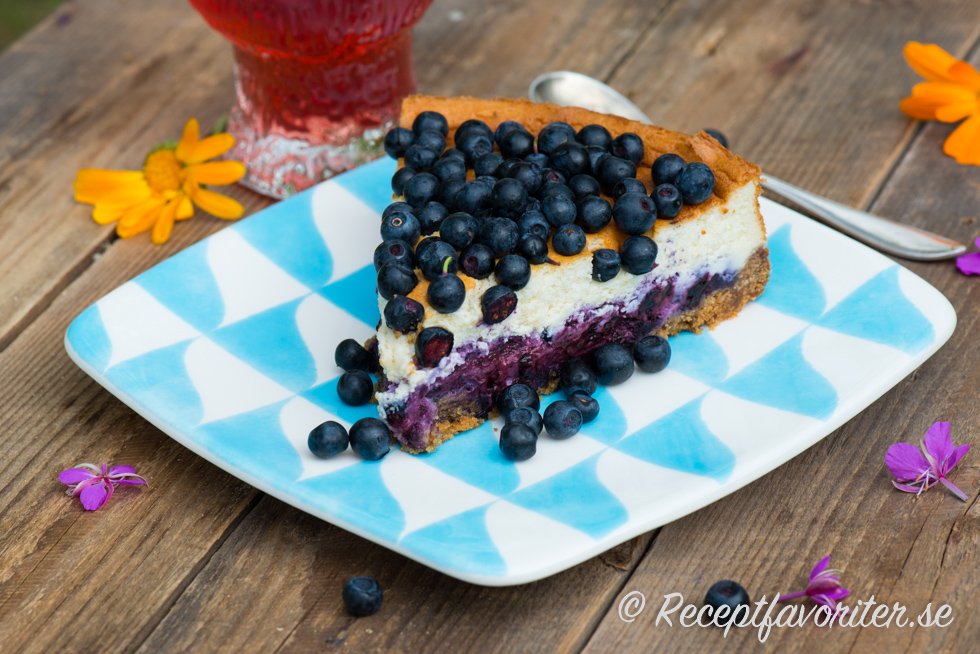 En bit bakad cheesecake med blåbär på tallrik En bit bakad cheesecake med blåbär på tallrik