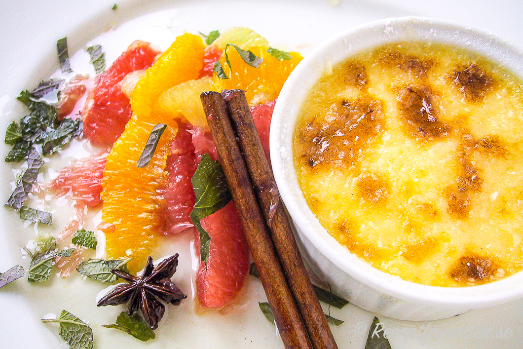 Crème brûlée med marinerad citrus på tallrik. Crème brûlée med marinerad citrus på tallrik.