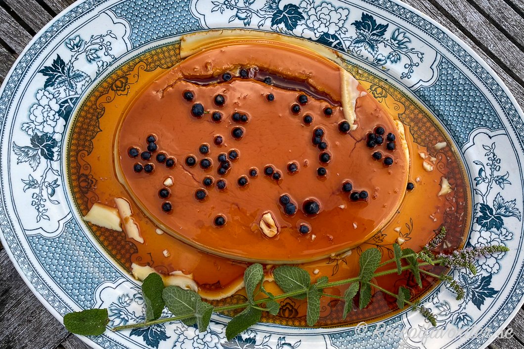 Crème caramel till flera i en stor form garnerad med färska blåbär och myntakvist. 